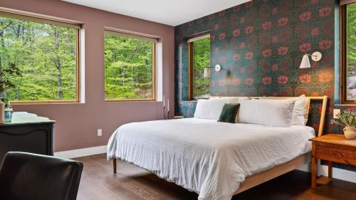 a bedroom with a bed and two windows at Bates Ridge by AvantStay in Tannersville