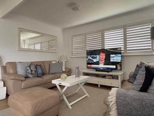 a living room with a couch and a flat screen tv at 2 Shore Ct - Shore Thing in Goolwa South