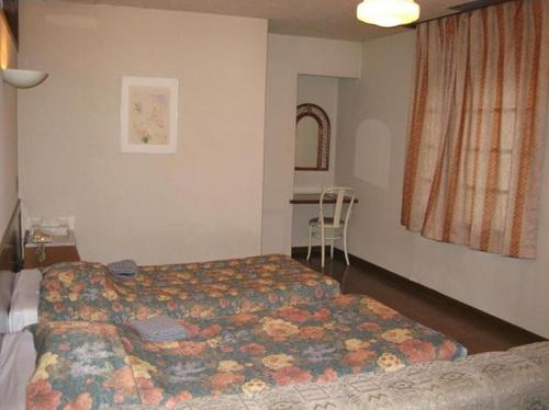 a hotel room with a bed and a chair at Hotel Civic Inn Sayama in Sayama