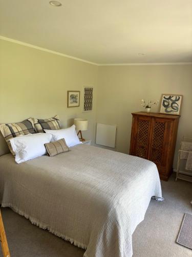 a bedroom with a large bed with white pillows at Lulu's Cottage by Native Forest in Waimauku