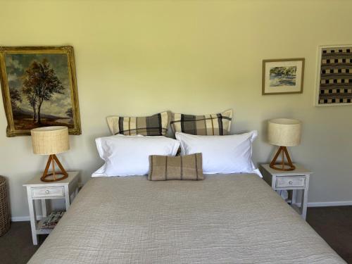 a bedroom with a bed with two lamps at Lulu's Cottage by Native Forest in Waimauku