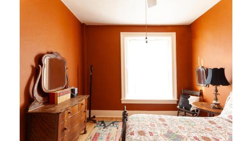 a bedroom with orange walls and a bed and a tv at Zane Grey in Cimarron