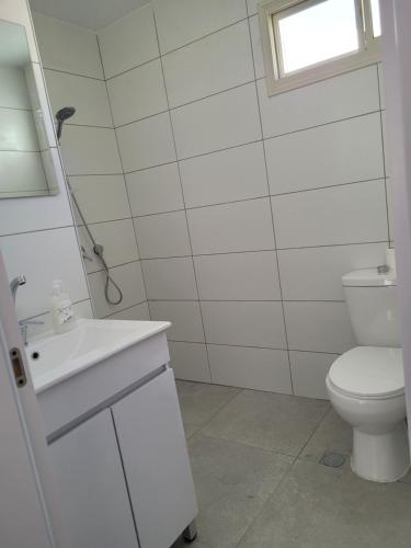 a white bathroom with a toilet and a sink at Serenity Apartment in Dalia in Dāliyat el Karmil