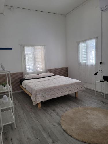 a bedroom with a bed and two windows and a rug at Serenity Apartment in Dalia in Dāliyat el Karmil