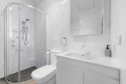 a white bathroom with a shower and a toilet and a sink at 15B Bolton Street in Berridale