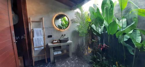 a bathroom with a sink and a mirror and plants at The Woods Uluwatu in Uluwatu