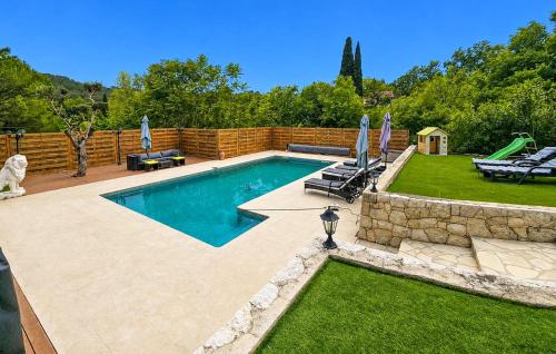 a swimming pool with chairs and umbrellas in a yard at Nice Home In Peymeinade in Peymeinade