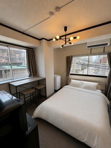 a bedroom with a large white bed and two windows at Palette Kuhonji in Kumamoto