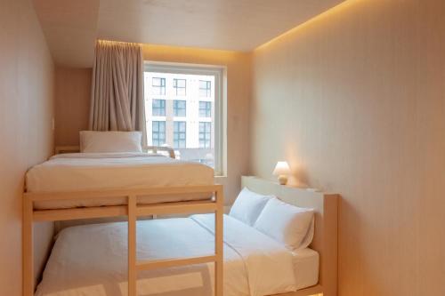 a small room with two beds and a window at yulstay in Seoul