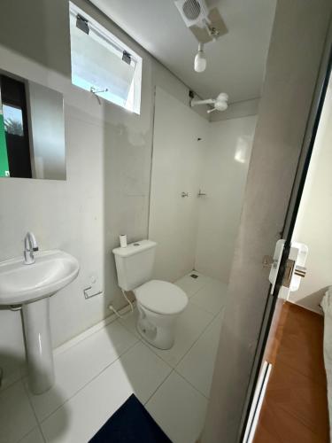 a white bathroom with a toilet and a sink at hotel paiol mutum in Nova Mutum