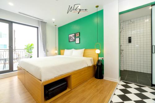 a bedroom with a bed and a green wall at Wilque Hotel Hanoi in Hanoi