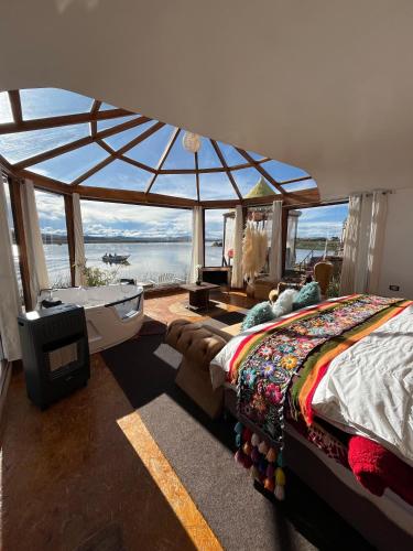 a bedroom with a bed and a tub and a large window at TiticacaMarkaLodge in Puno