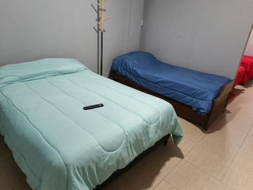 two beds in a room with a blue comforter at Hospedaje Don Antonio 1 in Tinogasta
