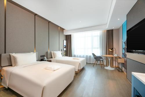 a hotel room with two beds and a television at Atour Hotel Lanzhou Xigu in Lanzhou