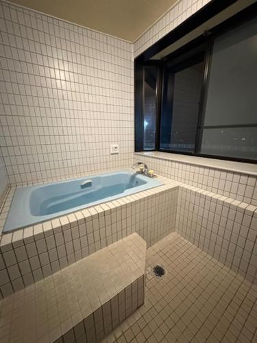 a bathroom with a bath tub with a window at はなれ香 in Kirishima