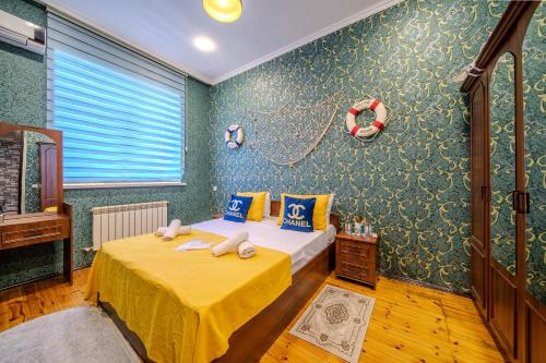 a bedroom with a bed with yellow sheets and blue wallpaper at Gabala Garden Harmony in Gabala