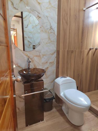 a bathroom with a white toilet and a sink at Pumaexplorer in Urubamba