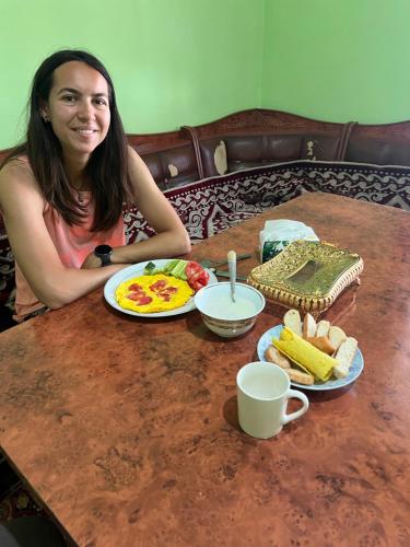 a woman sitting at a table with a plate of food at Fazenda guest house in Oktyabrʼskoye