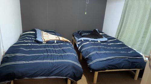 two beds sitting next to each other in a bedroom at 海辺の宿錦 b in Tomakomai