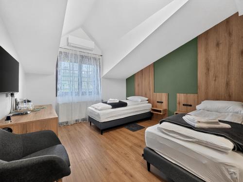 a bedroom with two beds and a chair and a couch at ParkNest - Apartmani i sobe in Apatin