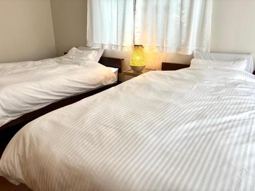 two white beds in a room with a window at 湘南で暮らすように泊まる一棟貸し U-house Shonan in Fujisawa