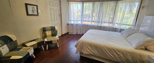 a bedroom with a bed and two chairs and a window at Lilly by the road in Durban