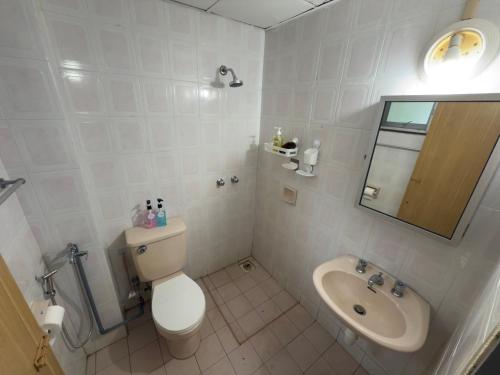 a white bathroom with a toilet and a sink at Tiktoki Apartment 15C Kijal in Kijal