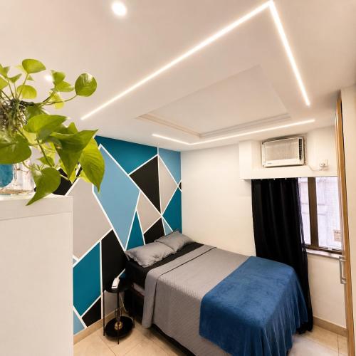 a bedroom with a bed and a blue wall at Apartamento completo e moderno com ar condicionado e piscina no centro do RIO in Rio de Janeiro