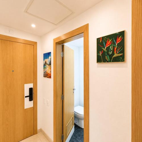 a bathroom with a toilet and a painting on the wall at Apartamento completo e moderno com ar condicionado e piscina no centro do RIO in Rio de Janeiro