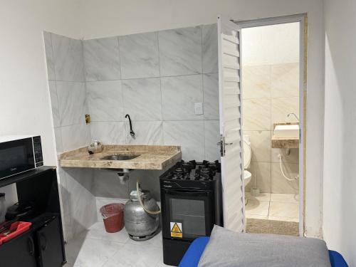 a small kitchen with a stove and a sink at Ap em bairro nobre com garagem e ar in Sobral