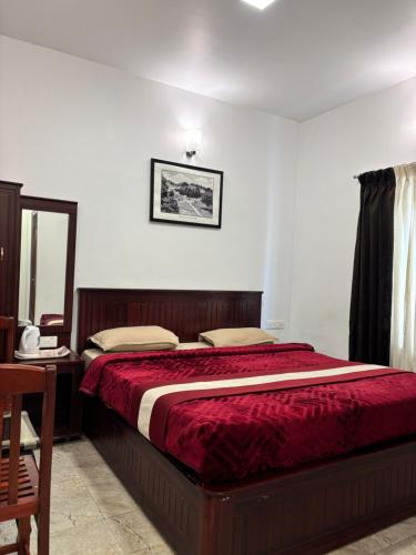 a bedroom with a bed with a red comforter at Green woods stays in Ooty