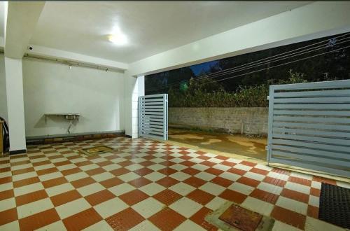 an empty room with a checkered floor and a large window at Green woods stays in Ooty