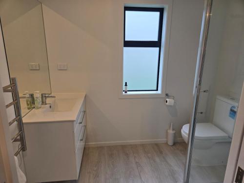 a bathroom with a sink and a toilet and a window at Stylish townhouse in Te Aroha