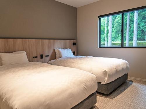 two beds in a room with a window at 水杜のすみか大野屋 in Fukui