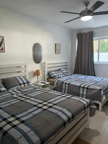 a bedroom with two beds and a ceiling fan at STEPS TO THE BEACH 2 Stunning condo 4 min walk to Bibijagua Beach and Catamarans in Punta Cana