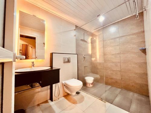 a bathroom with a toilet and a sink and a shower at The Raarees Mist Resort, Munnar - Nested in Nature's Lap in Munnar