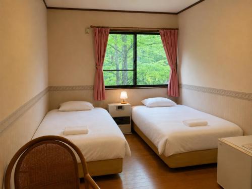 two beds in a room with a window at Anise Garden Lodge in Hakuba