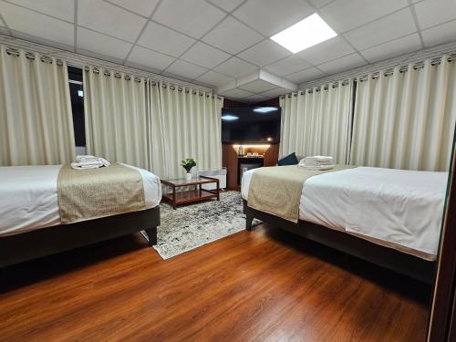 two beds in a room with wood floors and curtains at Casa Hotel Lago Titicaca in Puno