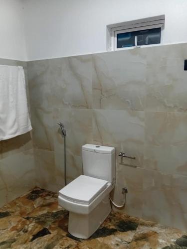 a white toilet in a bathroom with a window at 7C Villa in Galle