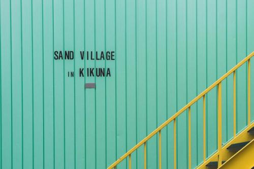 a sign on the side of a green wall at Sand Village Kikuna in Kikuna