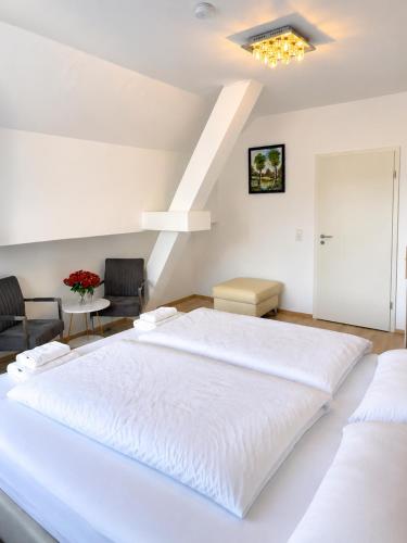 a large white bed in a room with two chairs at Einzelzimmer am Rheim Nierstein in Nierstein