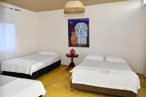 a room with two beds and a painting on the wall at HUAIRA Tatacoa in Villavieja