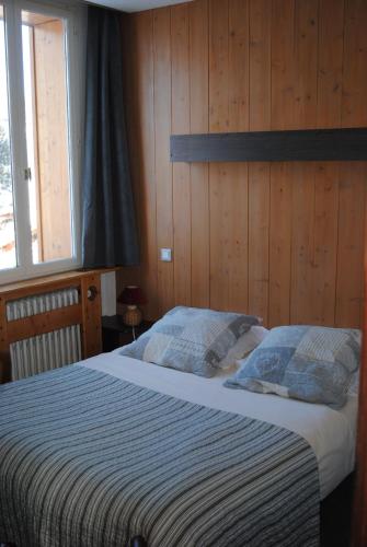 - une chambre avec un grand lit et des murs en bois dans l'établissement Hotel Val Joly, à Saint-Gervais-les-Bains