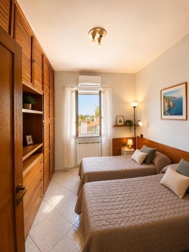 a hotel room with two beds and a window at Appartamento Casa di Sole Ischia in Ischia Town