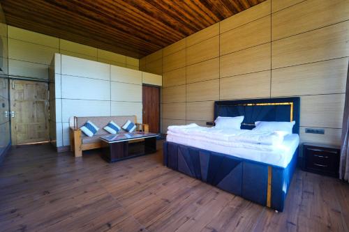 a bedroom with a large bed and a wooden wall at devdaar hills homes cafe & resort in Mussoorie