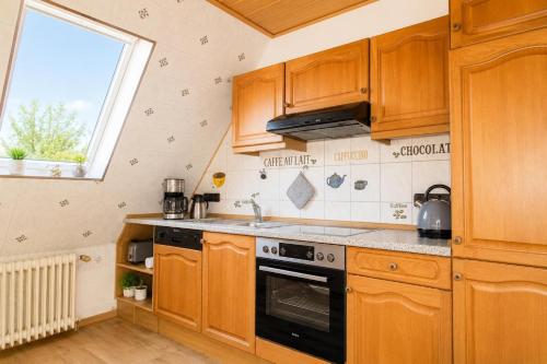 a kitchen with wooden cabinets and a stove top oven at Dünenlounge Dornumersiel in Dornum