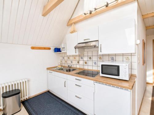 a kitchen with white cabinets and a microwave at Zum Süderwall in Esens