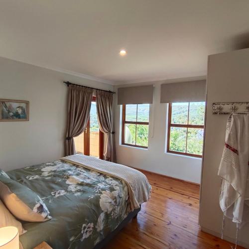 a bedroom with a bed and two windows at Zion's Rest in Barrydale