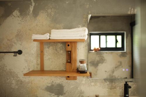 a bathroom with a shelf with towels and a mirror at 私藏52 九份金瓜石民宿 旅宿攝影 in Ruifang