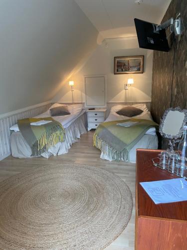 a bedroom with two beds and a desk and a rug at skummeslöv B & B in Laholm